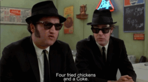 A frame from Blues Brothers where John Belushi is ordering four fried chickens and a coke.